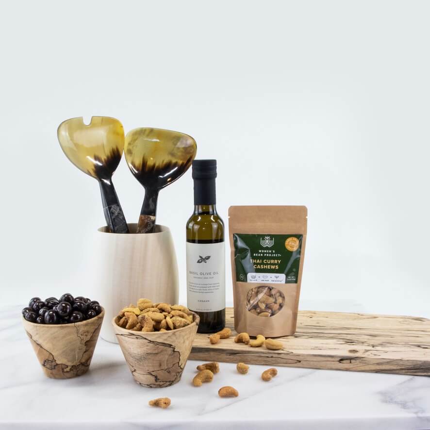 the warmth of wood Gift set: a wooden charcuterie board, two handcrafted bowls, a wooden vase, salad tongs, a bottle of organic olive oil, and cashews