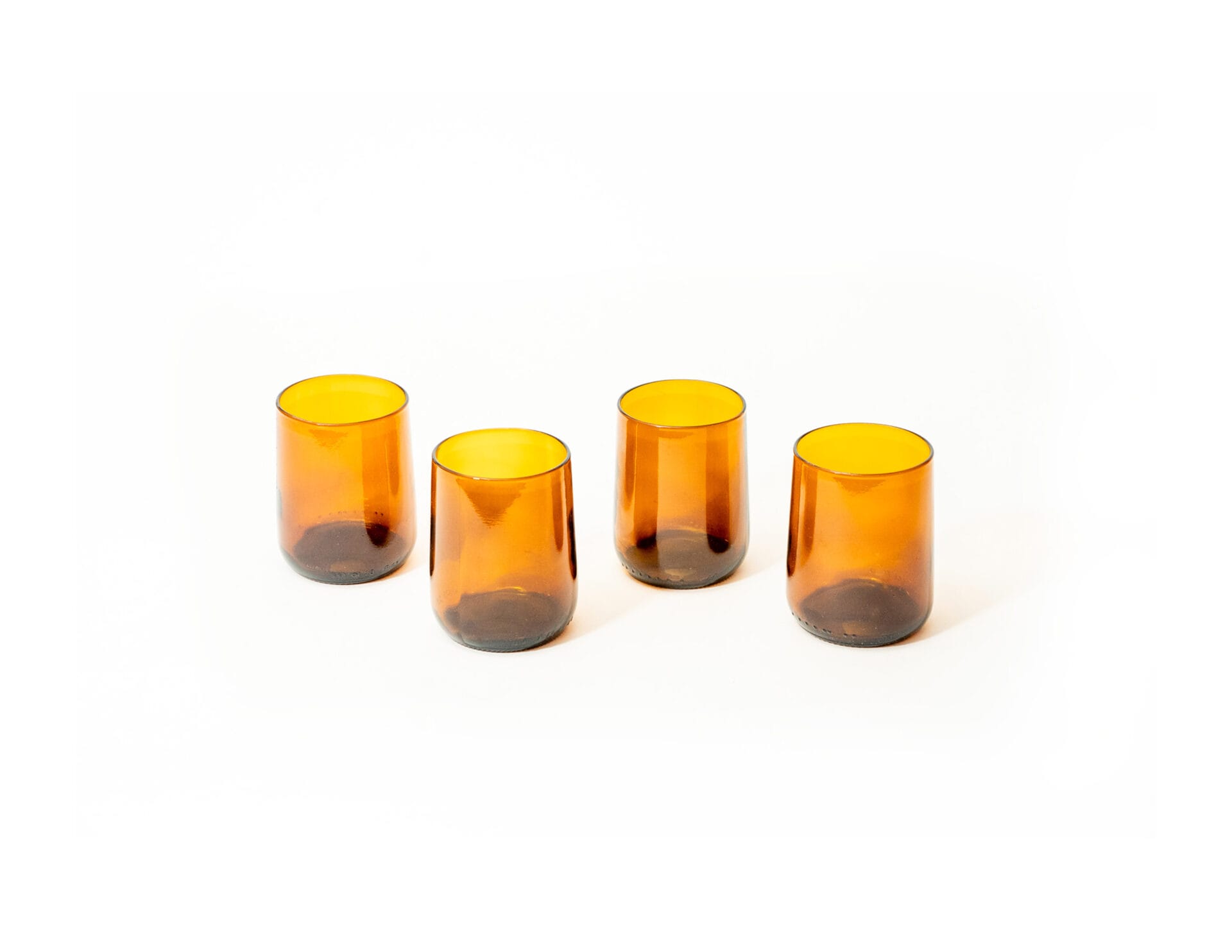 4 amber gronn glasses phototgraphed from slightly above 4 simple upcycled amber glasses made from Modelo beer bottles photographed from slightly above
