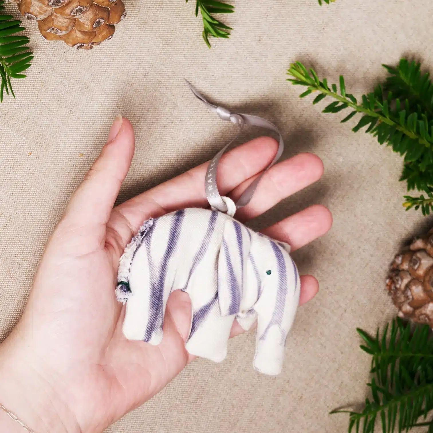 "Wise Tusker" Elephant Ornament MADE51 a small elephant ornament made out of cloth is held gently in a hand