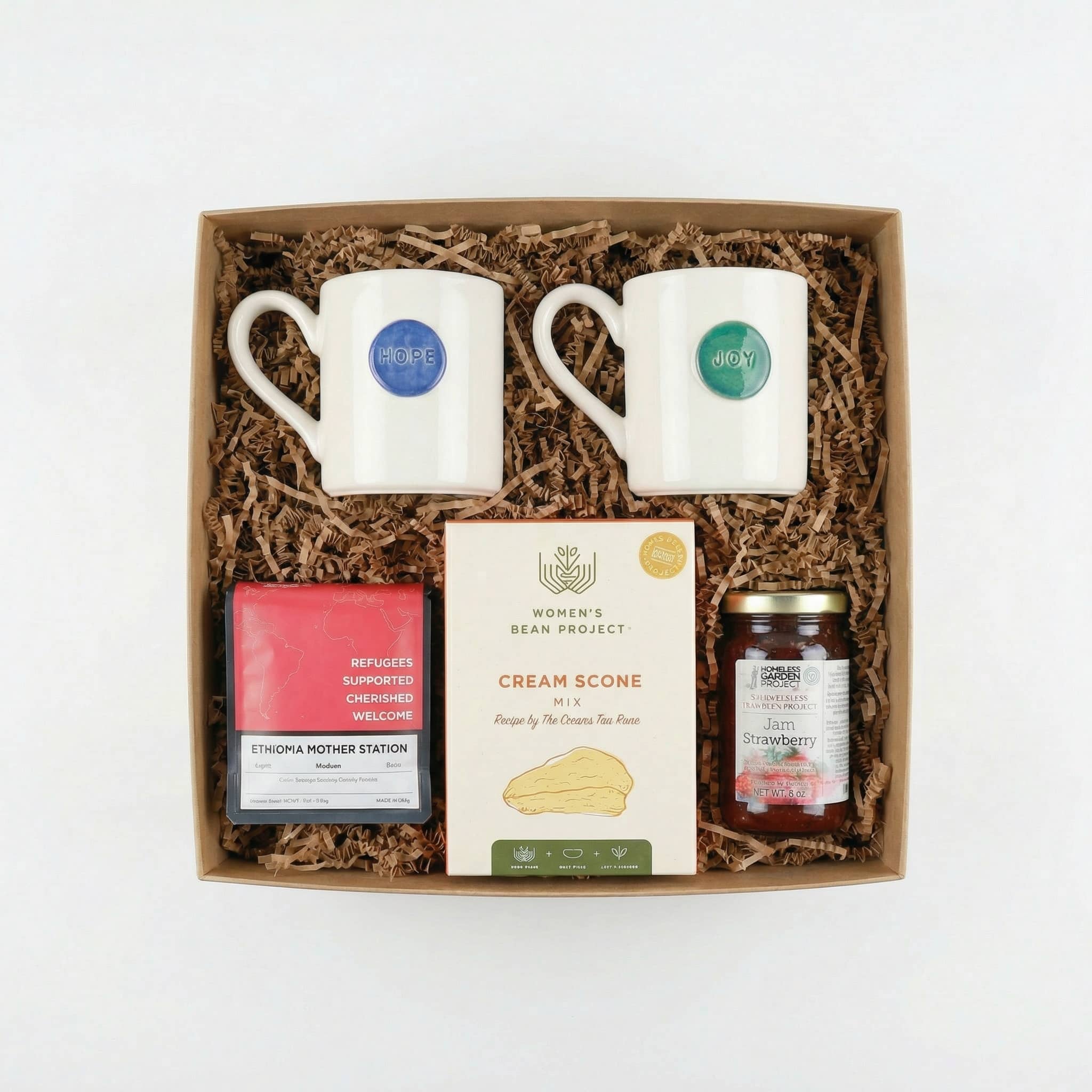 a gift set in a gift box with two coffee mugs, coffee, scone mix, and jam