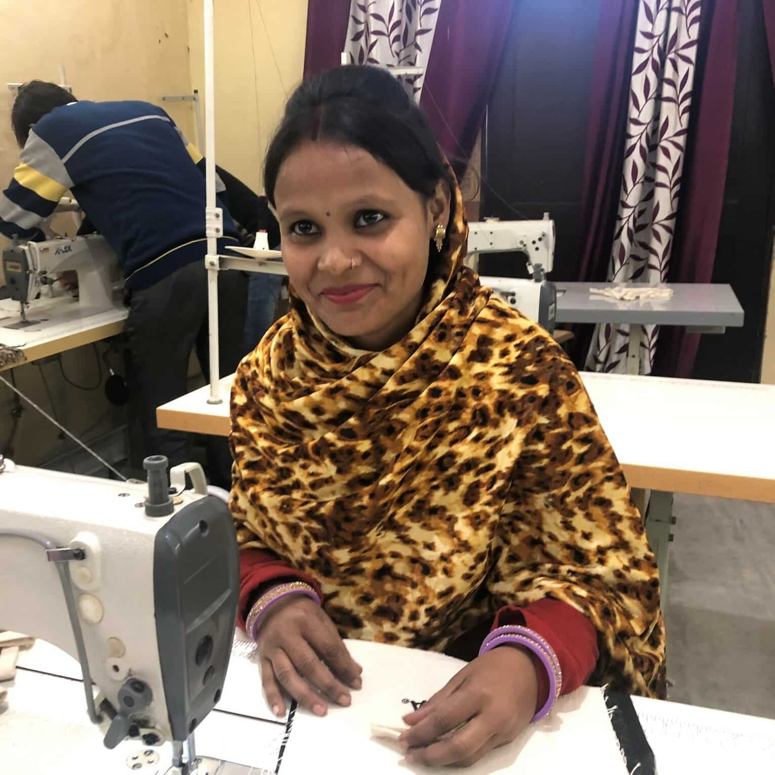 A worker sits at a sewing machine, smiling A worker sits at a sewing machine, smiling