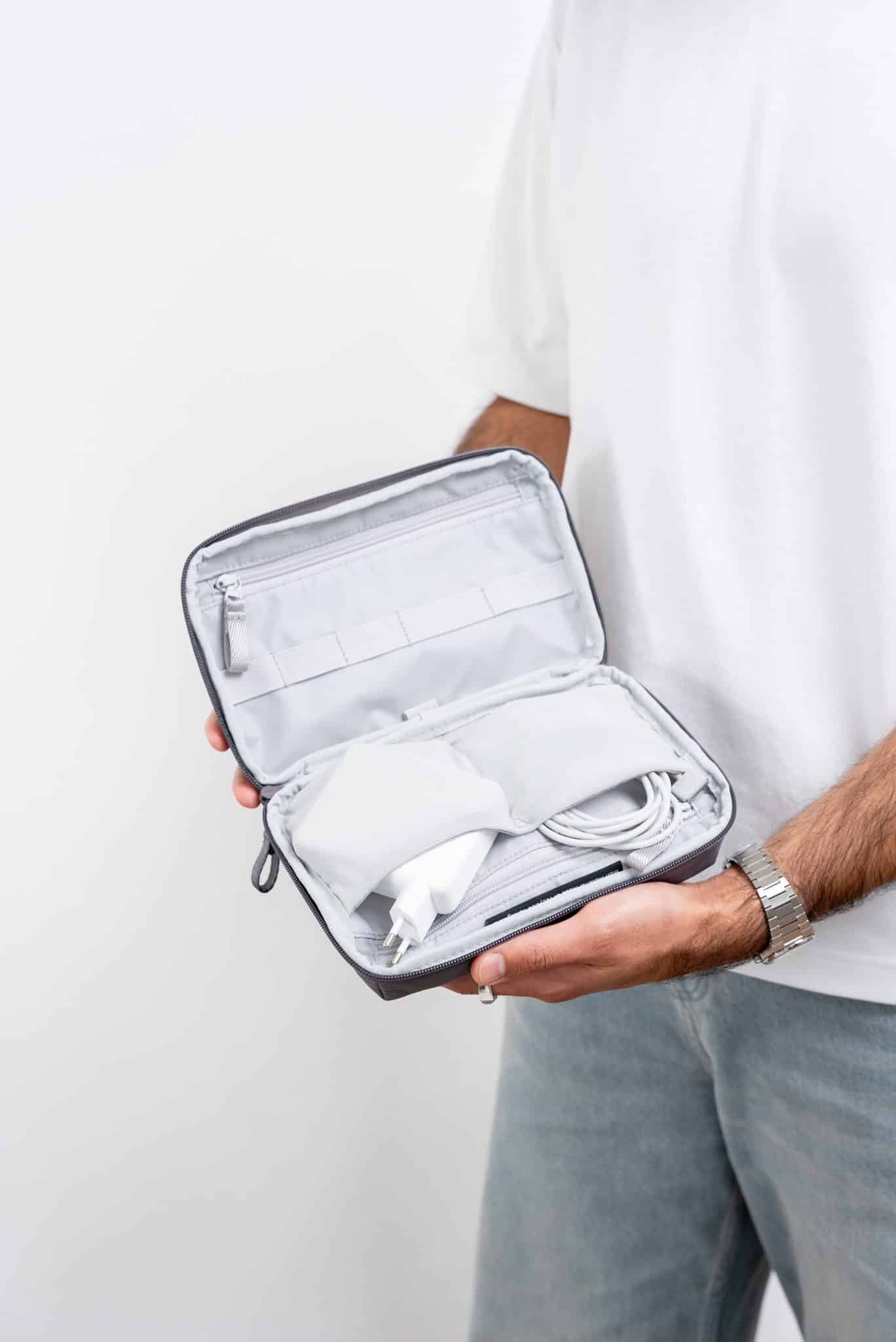 GOT bag COMMUTER TECH POUCH two hands holding a tech pouch open, showing inner compartments and stored chargers