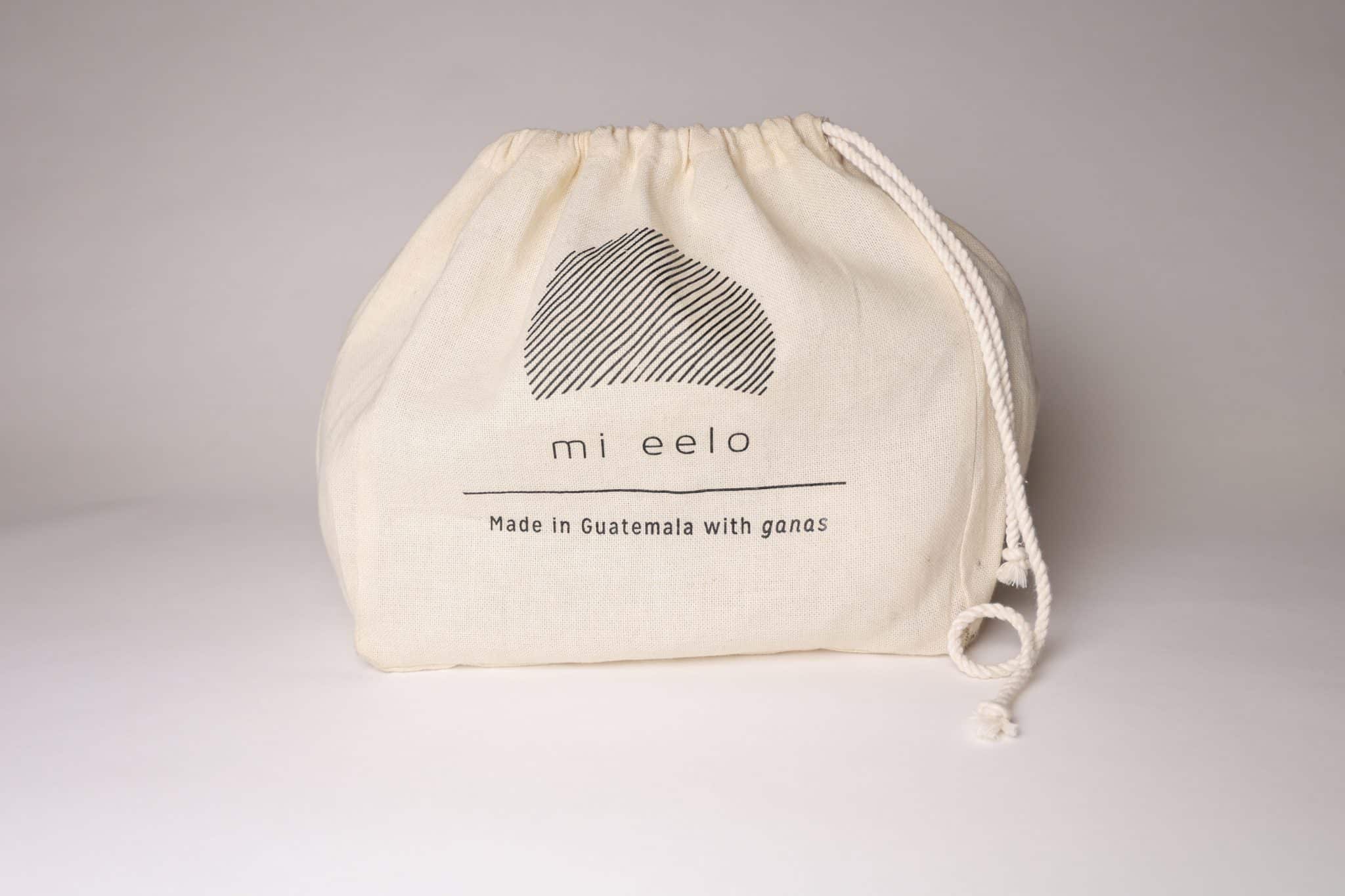 mi eelo drawstring gift bag A cream-colored drawstring muslin bag with a simple corporate logo sits against a white background