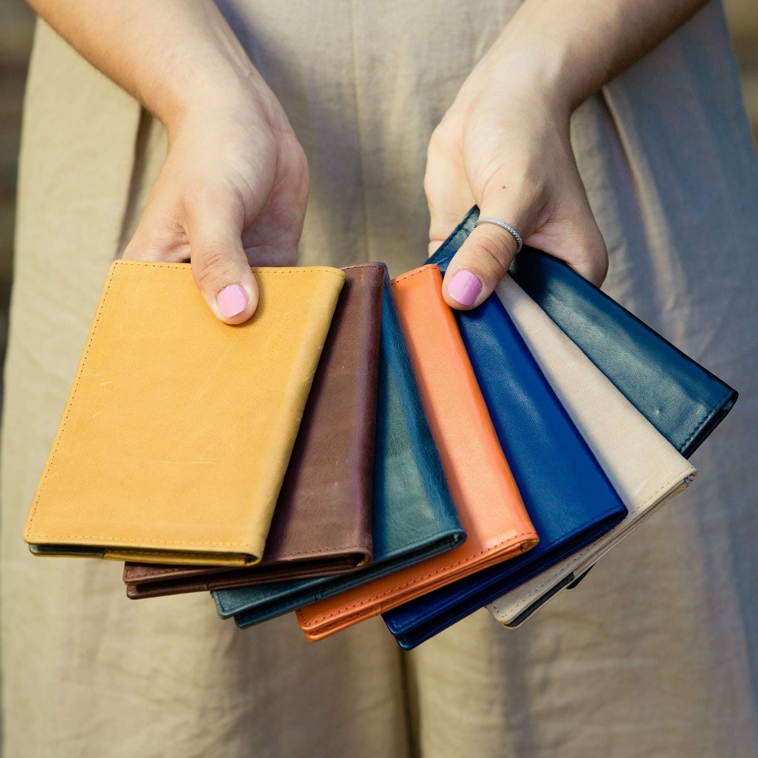 Dokmai Leather Passport Holders a collection of different colored passport holders being held in a woman's hands