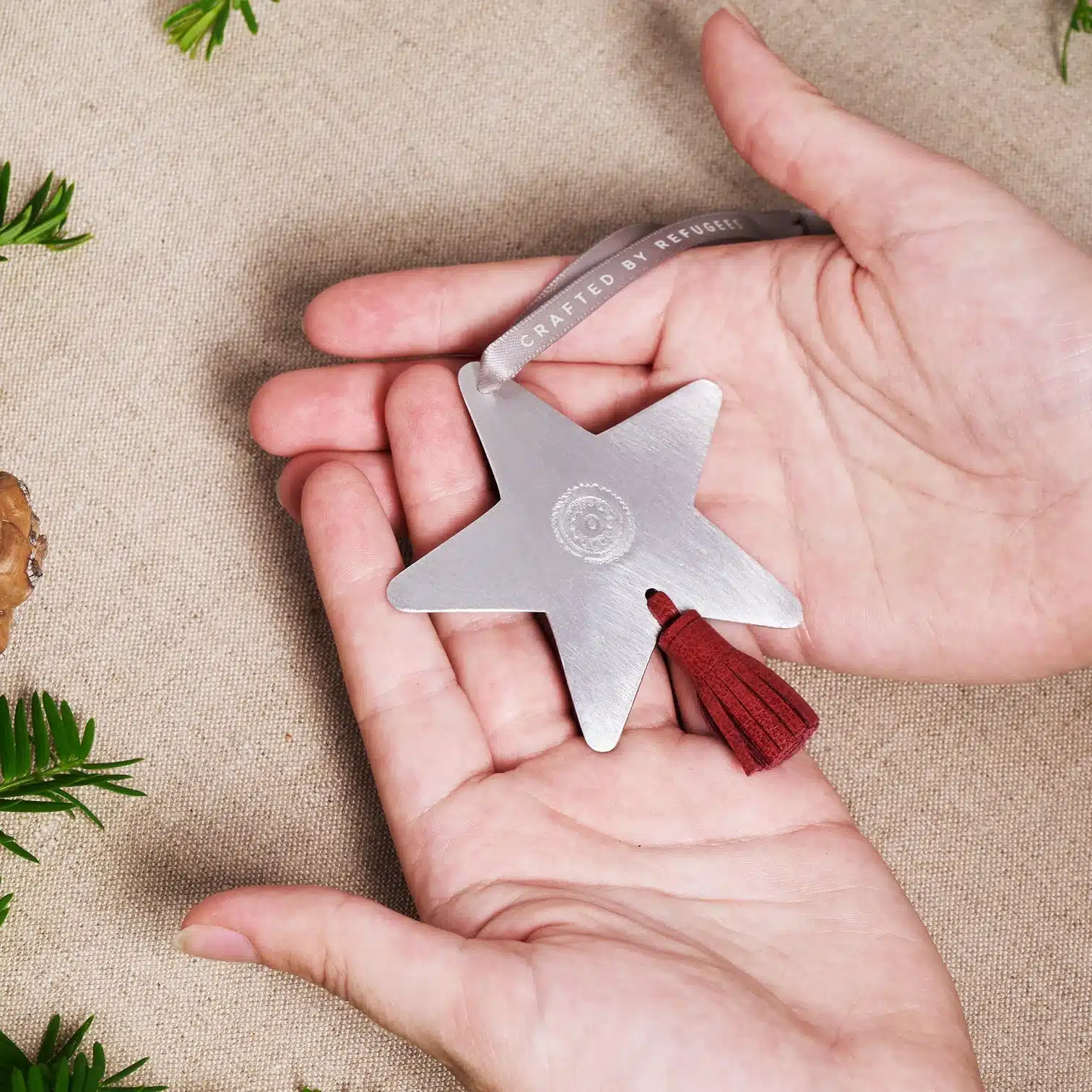 Shooting Star Ornament MADE51 a delicate metal star-shaped ornament is held gently in two hands